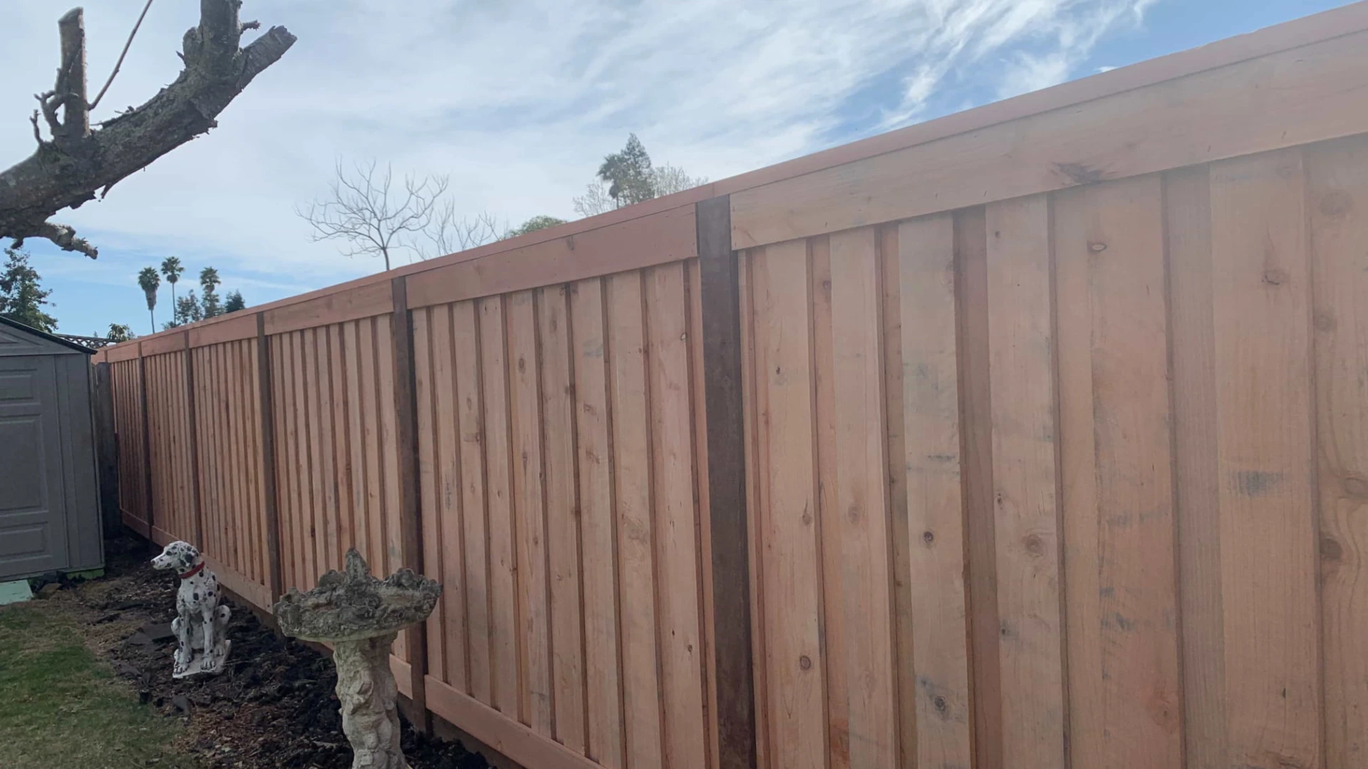 wooden fence with bird bath and dog statue near by