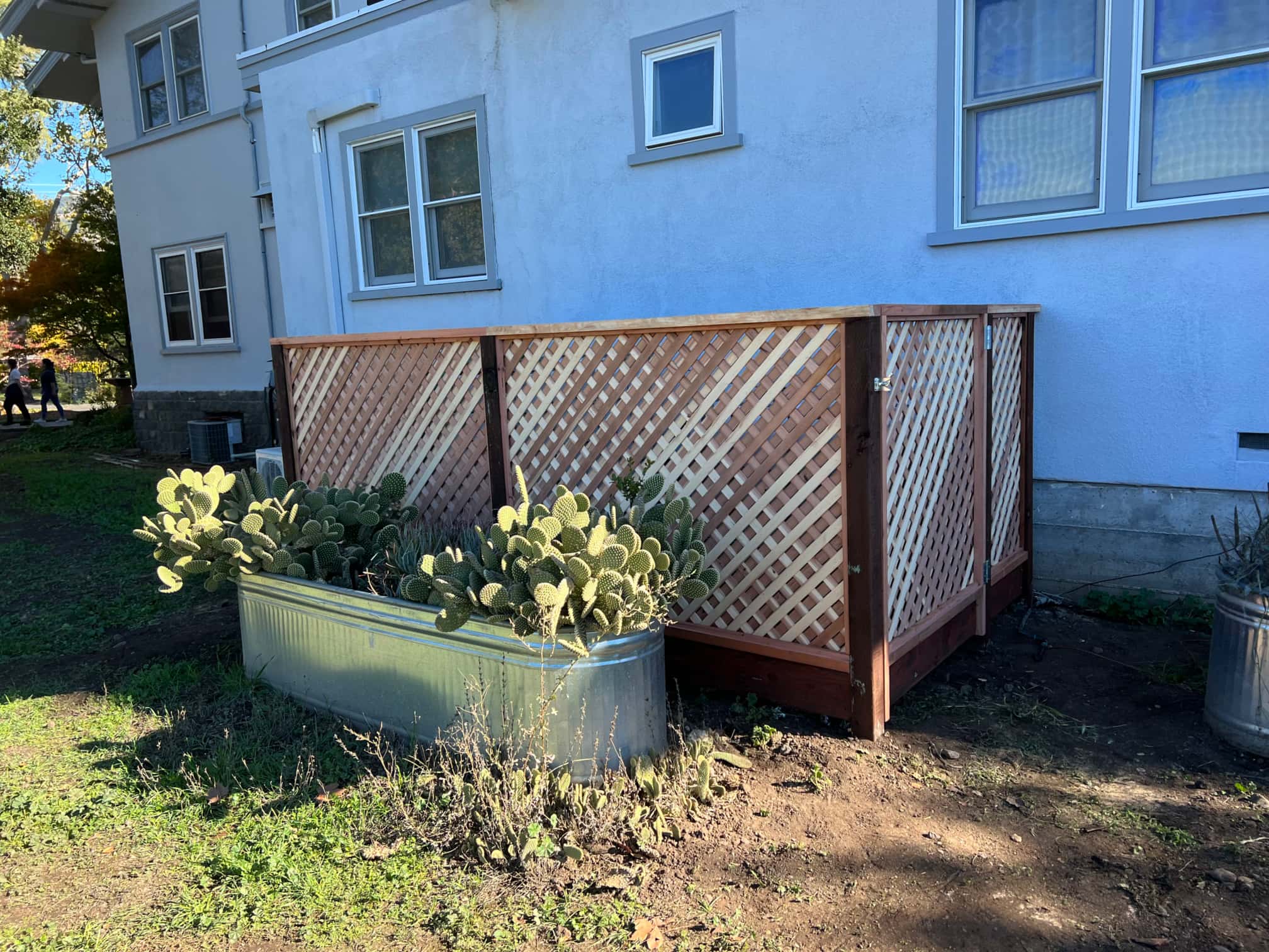 wooden trash enclosure with cactuses near by